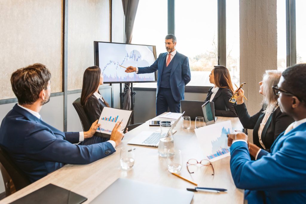 Equipo profesional analizando gráficos financieros y datos en pantalla durante una reunión de seguimiento.