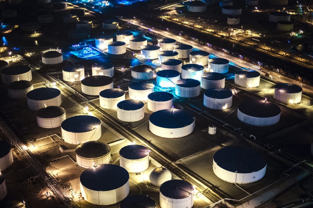 Tanques industriales de almacenamiento de combustible iluminados durante la noche en una instalación energética.